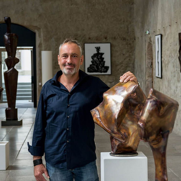 Künstler mit Hand auf seiner Bronzeskulptur